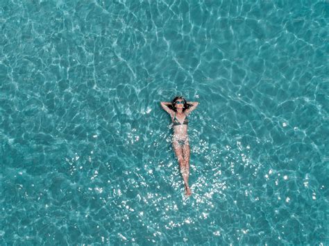 Beautiful Young Woman Floating In Crystal Clear Water Aerial Shot Stock