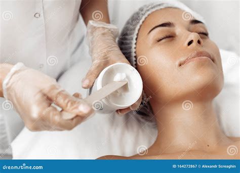Cosmetologist Applying Cream On Female Face In Cosmetology Salon Stock