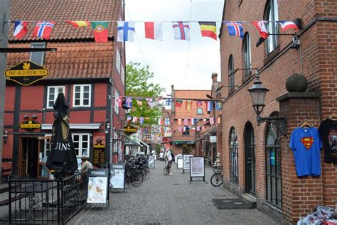 A Cobblestone Street Lined With Brick Buildings And Flags Hanging From