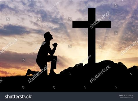 Concept Of Religion Silhouette Of A Man Praying Before A Cross At