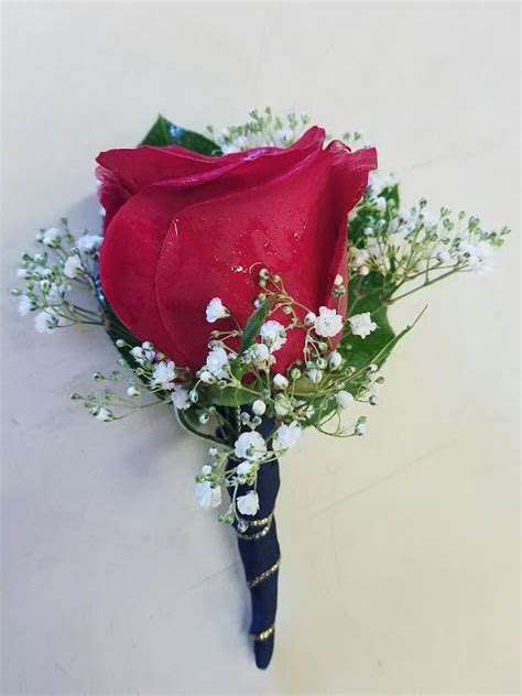 A Single Red Rose Boutonniere With Babys Breath Green Leaves And Navy