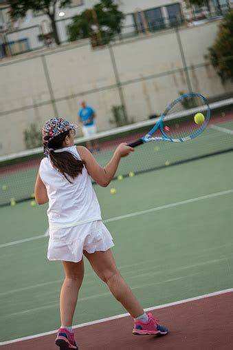 A Girl Is Playing Tennis With Her Tennis Coach On The Hardcourt Shooting Forehand And Backhand