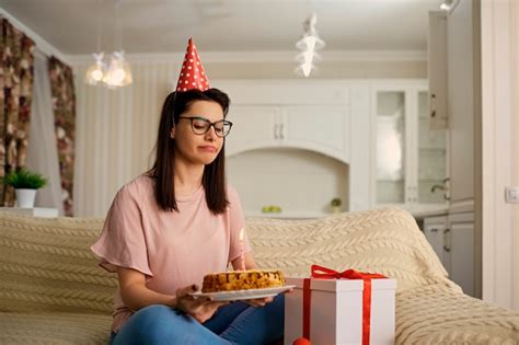 premium photo an unhappy girl wearing a hat on her birthday with a cake with candles is alone