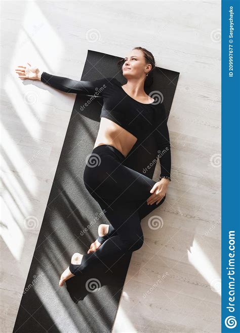 A Woman In Black Sportswear Practicing Yoga While Lying On A Gymnastic