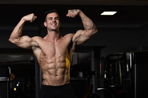 Premium Photo Bodybuilder Performing Front Double Biceps Pose In Gym
