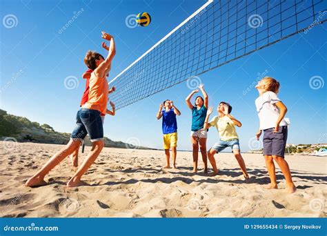 Muchachos Y Muchachas Que Juegan A Voleibol En La Playa Foto De Archivo