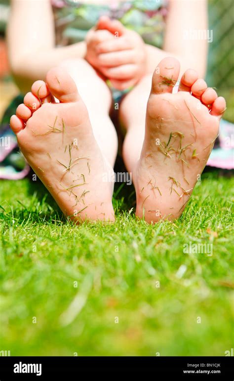 Four Year Old Girl In A Garden With Grass Cuttings On The Soles Of Her