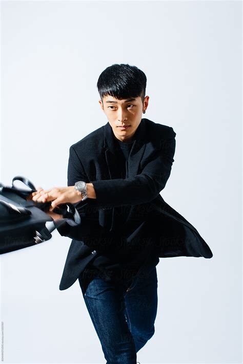 Portrait Of An Asian Man Wearing A Black Suit Over White Background