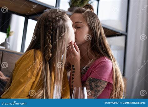 Dos Lesbianas Con Copa De Vino Besándose En El Salón Imagen de archivo Imagen de bisexual