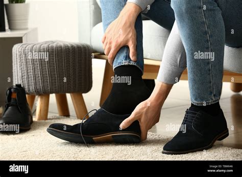 Young Man Putting On Shoes In Room Stock Photo Alamy