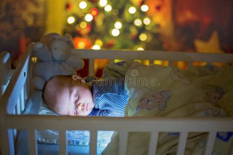 Adorable Newborn Baby Boy Sleeping In Crib At Night Stock Photo