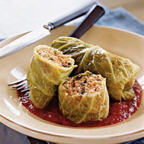 Three Stuffed Cabbages Are On A Plate With Sauce And A Fork Next To It