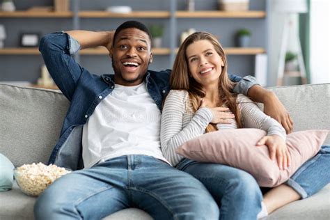couple s leisure happy interracial lovers watching tv and eating popcorn at home stock image