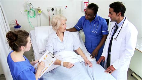 caring medical staff discusses treatment procedures with an old caucasian hospital patient stock