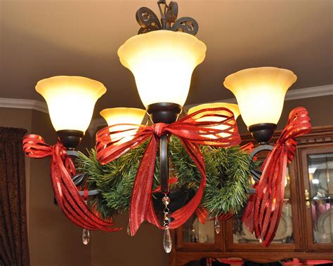 simple way to decorate a dining room light with garland, red bows and