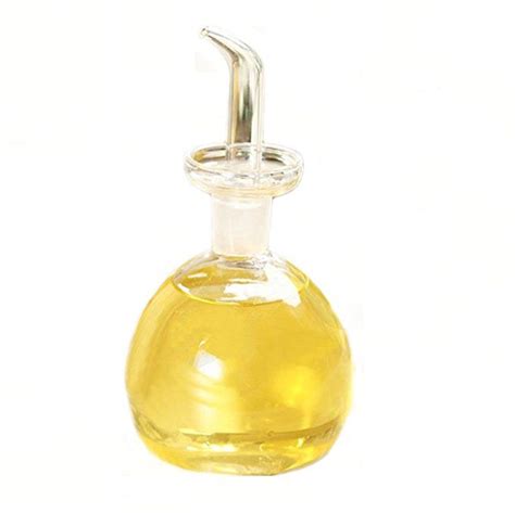 a glass bottle filled with yellow liquid on top of a white table next to a metal hook