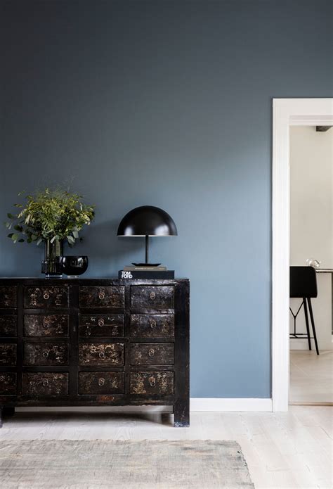 A Living Room With Blue Walls And A Black Lamp On Top Of A Dresser Next