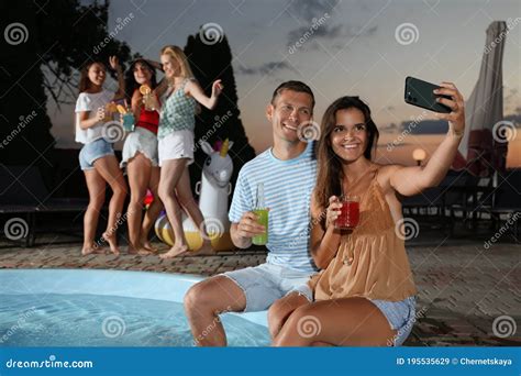 Happy Couple With Refreshing Drinks Taking Selfie At Pool Party In Evening Stock Image Image