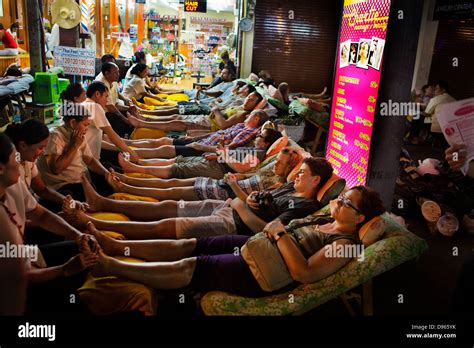 tourists and locals lie down in rows for traditional thai foot massage in khao san road stock