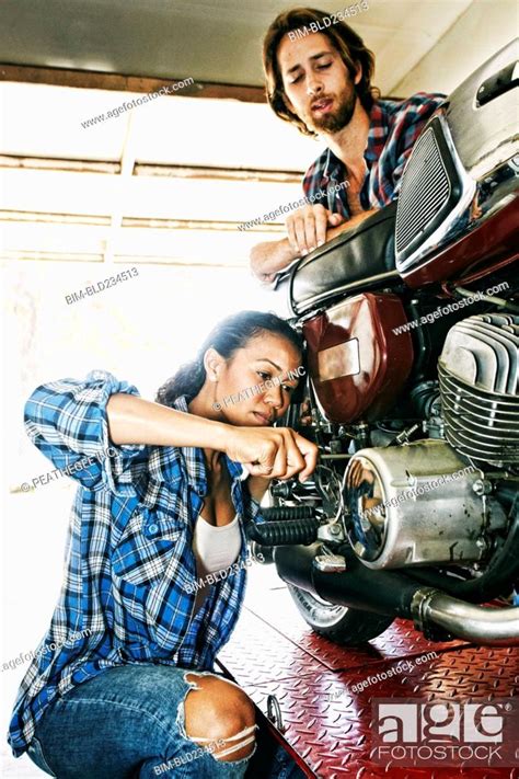 Man Watching Woman Repairing Motorcycle In Garage Stock Photo Picture