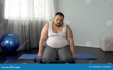 Exhausted Fat Man Sitting On Floor With Dumbbells Tiring Workout