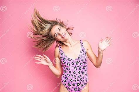 Slim Blonde Woman In Pink Leopard Swimsuit With Flowing Hair On A Pink