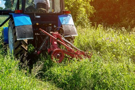 Farm Tractor Green Mowing High Grass In A Sunny Summer Day Stock Photo