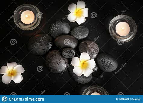 beautiful composition with spa stones flowers and burning candles on black background top view