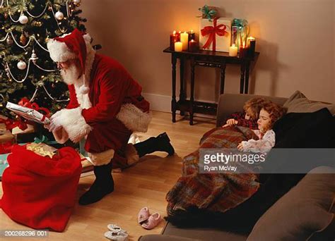 Santa Putting Presents Under Tree Photos And Premium High Res Pictures