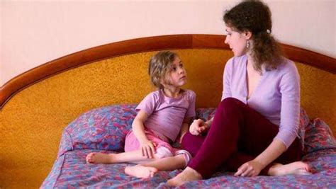 Mother Sits On Bed With Her Little Daughter And Tells Her About