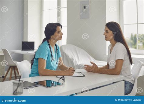 Woman Nurse Or Doctor Listening To Patients Complaints During Visit In