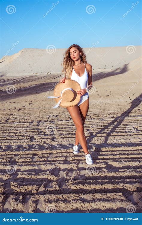 A Woman Walks On The Sandy Beach Rest Walks In Body Swimsuits Straw