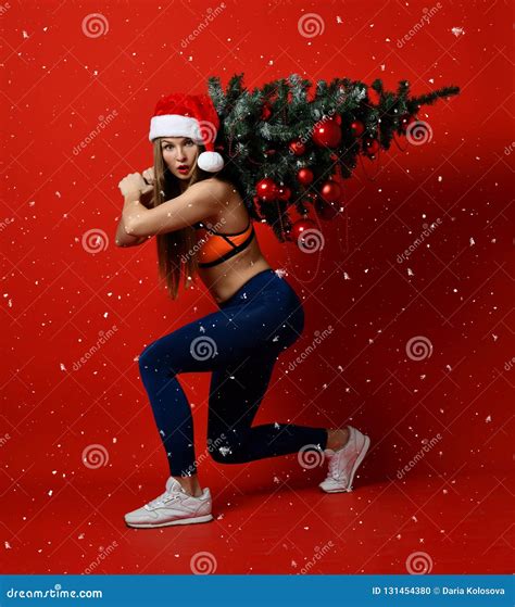 Christmas Fitness Sport Woman Wearing Santa Hat Holding Xmas Tree On Her Shoulders Snowflakes