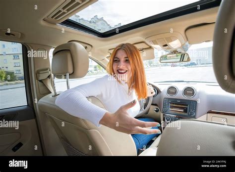 Wide Angle View Of Young Redhead Woman Driver Driving A Car Backwards