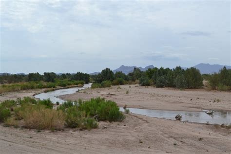 A River Running Through A Desert Landscape With Mountains In The Background