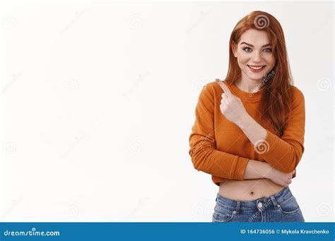 sassy cute flirty redhead silly woman wear makeup lipstick pointing upper left corner smiling