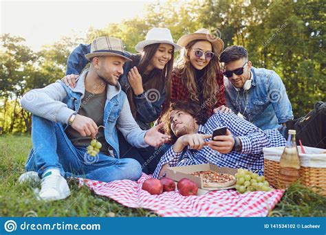 Young People Laugh Sitting On The Grass At A Picnic Stock Photo