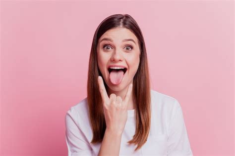 Premium Photo Surprised Young Woman Show Horns Stick Tongue Out Mouth Over Pink Background
