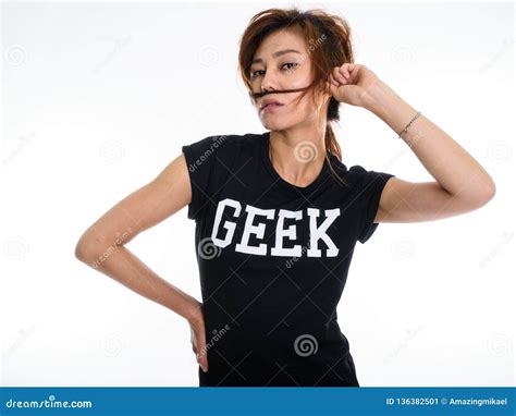 Studio Shot Of Young Asian Geek Girl Playing With Her Hair As Mu Stock