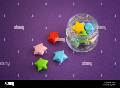 Colorful Origami Lucky Stars Spilling Out Of A Jar Purple Background