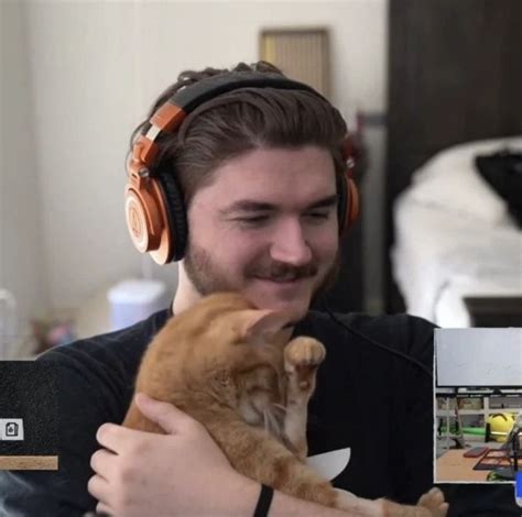 A Man Wearing Headphones Holding An Orange Cat