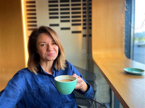 Close Up Of Cheerful Caucasian Beautiful Businesswoman Sitting In Coffee Shop Holding Cup Of