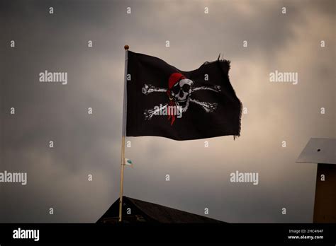 Low Angle Shot Of A Waving Pirate Flag With A Skull Under Storm Clouds