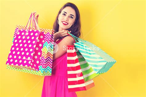 Joyful Woman With Multiple Shopping Bags On A Yellow Backdrop Royalty
