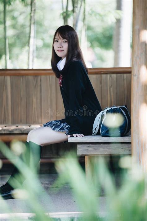 colegiala japonesa joven del retrato que se sienta en jardín japonés y el bosque de bambú foto