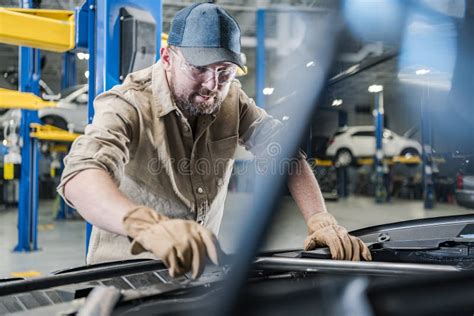 Dealership Auto Service Technician Worker Performing A Car Maintenance