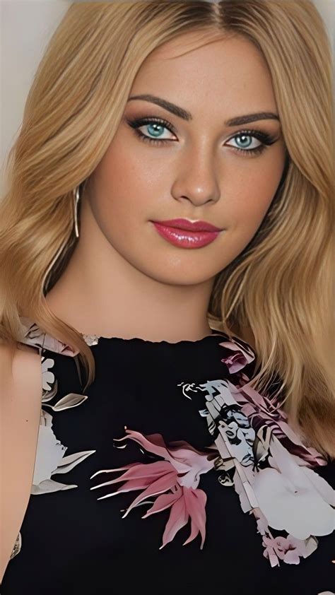 A Woman With Blonde Hair And Blue Eyes Is Wearing A Black Floral Dress
