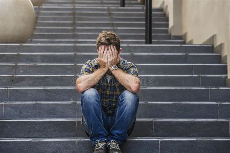 Young Sad And Desperate Man Sitting Outdoors At Street Stairs Suffering