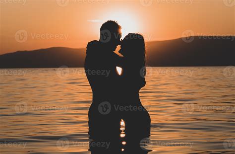 Silhouettes In Love Romantic Couple Lovers Hugging Kissing Touching Eye Contact At Sunset