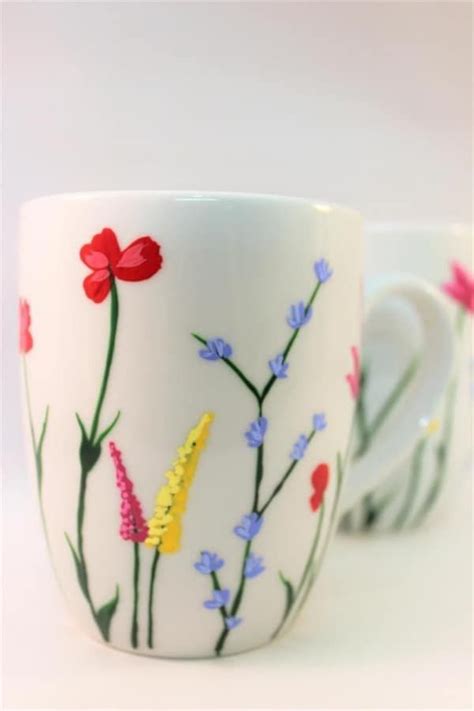 Two Coffee Mugs With Flowers Painted On Them One Has An Arrow Pointing